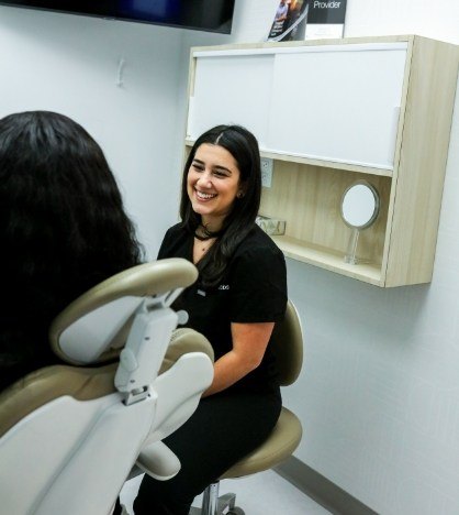 Woman in gray sweater smiling at her dentist