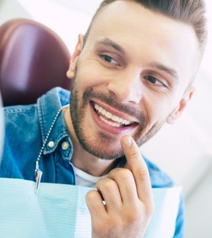 Man pointing to his smile while visiting cosmetic dentist in New York
