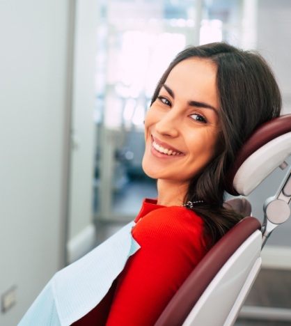 Woman in red shirt grinning in dental chair