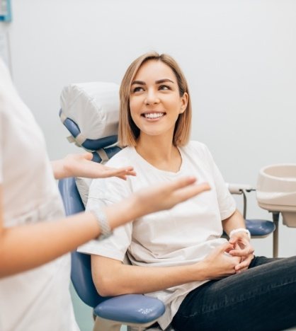 Woman smiling while listening to her dentist talk