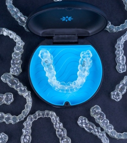 Several Invisalign aligners with one pair in their carrying case