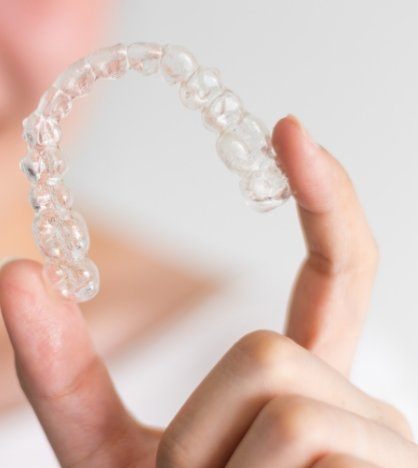 Smiling person holding an Invisalign tray
