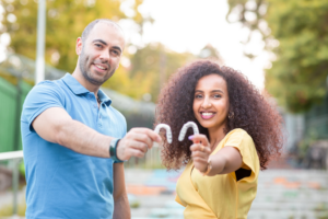 a couple smiling and holding their Invisalign aligners