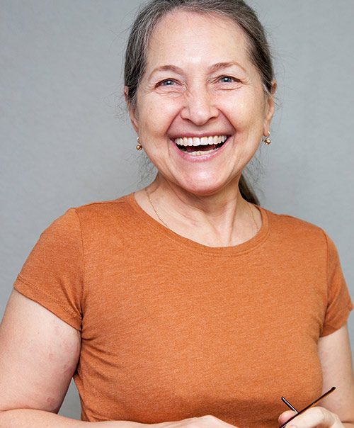 Smiling woman in orange shirt after cavity treatment at our Gramercy Park dentist for tooth decay in NYC