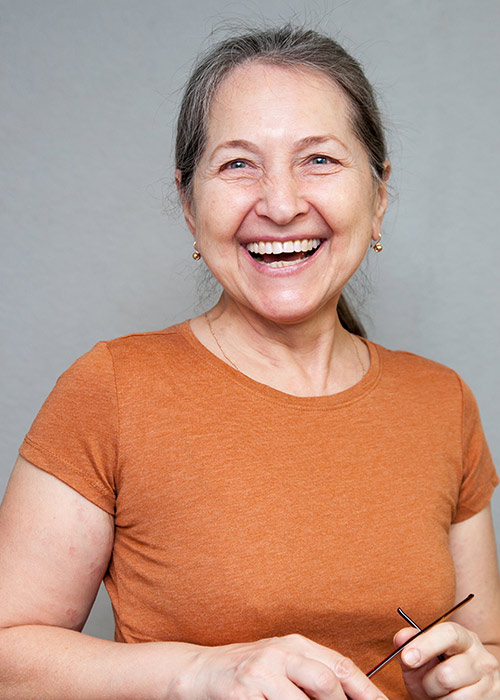 Smiling woman in orange shirt after cavity treatment at our Gramercy Park dentist for tooth decay in NYC