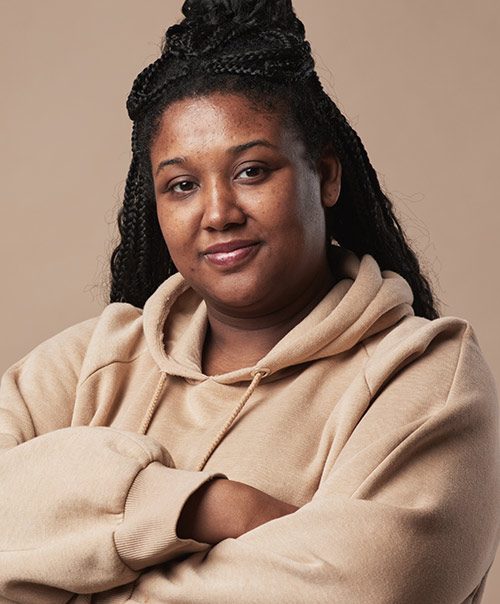 Woman with braided hair and arms crossed in a beige hoodie at Lux Smiles NYC TMJ clinic in Gramercy Park