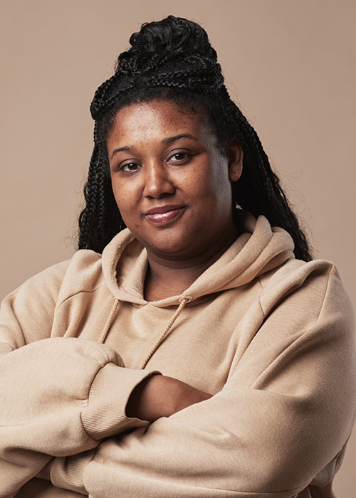 Woman with braided hair and arms crossed in a beige hoodie at Lux Smiles NYC TMJ clinic in Gramercy Park