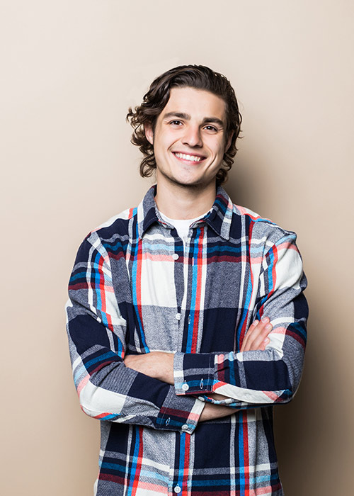 Smiling young man with arms crossed after dental fillings at our New York clinic in Gramercy Park