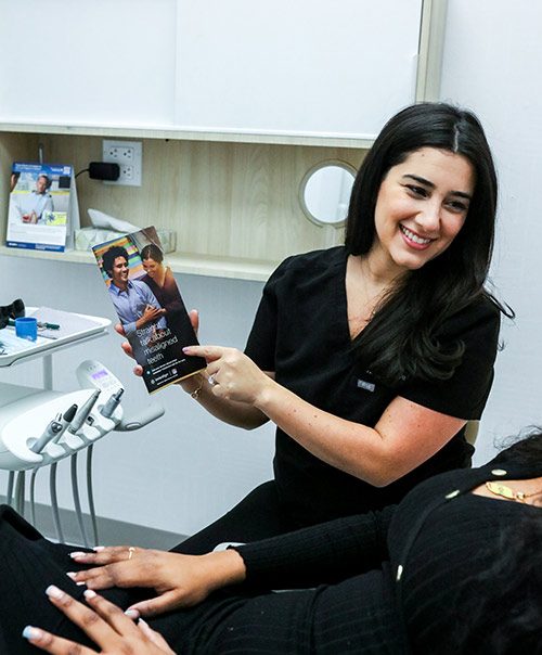 Smiling dentist showing patient an Invisalign clear aligners brochure at our Gramercy Park NYC clinic