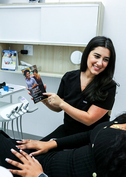 Smiling dentist showing patient an Invisalign clear aligners brochure at our Gramercy Park NYC clinic