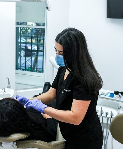 Dentist in black scrubs and mask treating a reclined patient at our Gramercy Park clinic in New York, NY