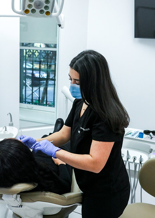 Dentist in black scrubs and mask treating a reclined patient at our Gramercy Park clinic in New York, NY