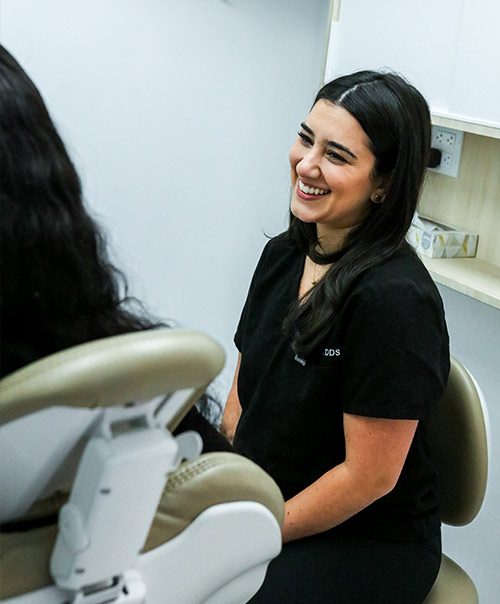 Smiling DDS dentist chatting with a patient in the dental chair at our New York dental bridges clinic