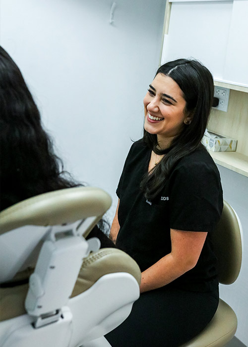 Smiling DDS dentist chatting with a patient in the dental chair at our New York dental bridges clinic