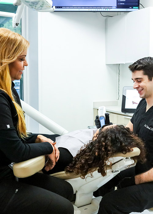 Lux_500_pt1 Periodontist and hygienist comforting a patient during gum disease treatment at Lux Smiles in New York